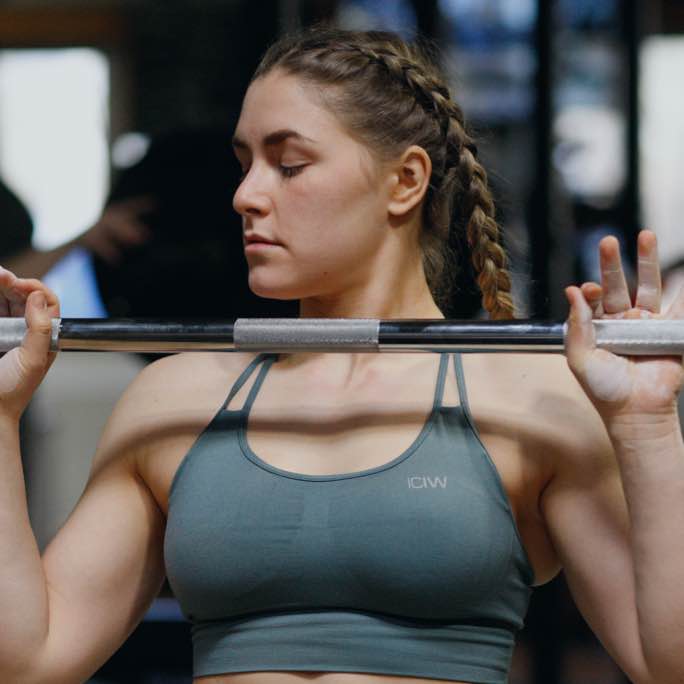 Ein symbolisches Bild von einer trainierenden Frau, die ein Krattraining mit der Langhantel absolviert